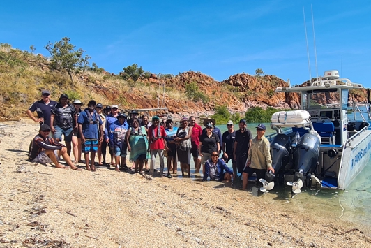 Group of people standing next to boat on shoreline