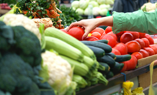 Hands of a female picking fresh vegetables from a cart