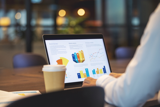 Close up of businessman using a laptop with graphs and charts on a laptop computer