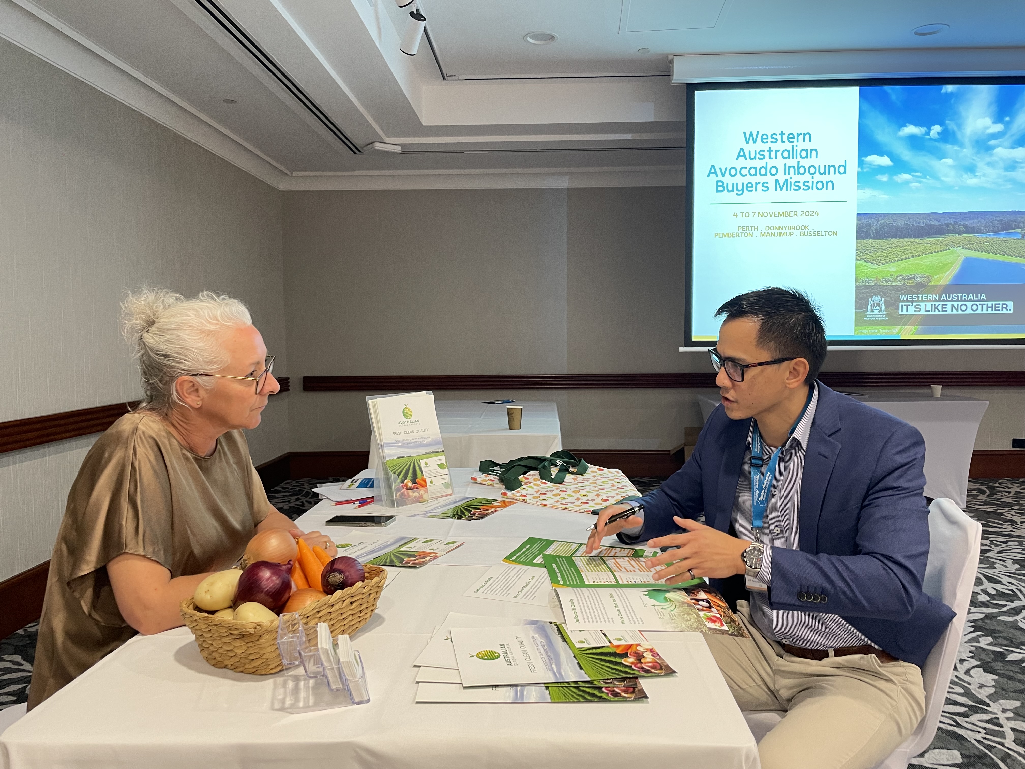 A female and male sitting at a table with fresh produce and having a discussion