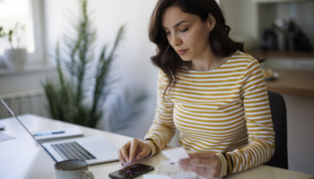 Person at table with laptop and calculator